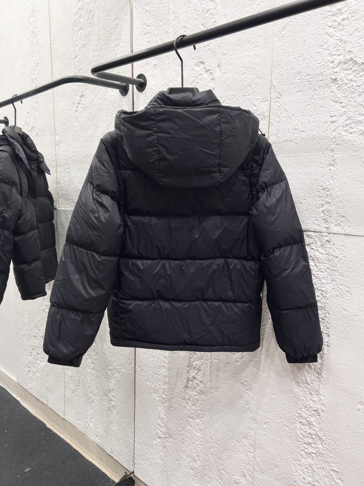 Moncler long puffer jacket back view on hanger, dark quilted puffer with hood