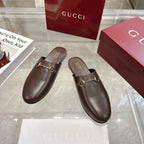 Gucci unisex dark leather mule loafers with gold horsebit detail and rounded toe.