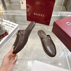 Gucci unisex leather horsebit mules with rounded toe, shown with a hand for scale.