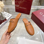 Gucci tan leather mule slide with gold-tone horsebit detail, held by hand