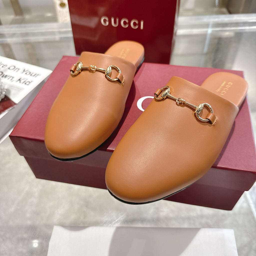 Gucci tan leather slide mules with gold-tone horsebit hardware, angled view