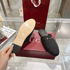 Gucci unisex mules with dark monogram upper; hand holds light sole underside view