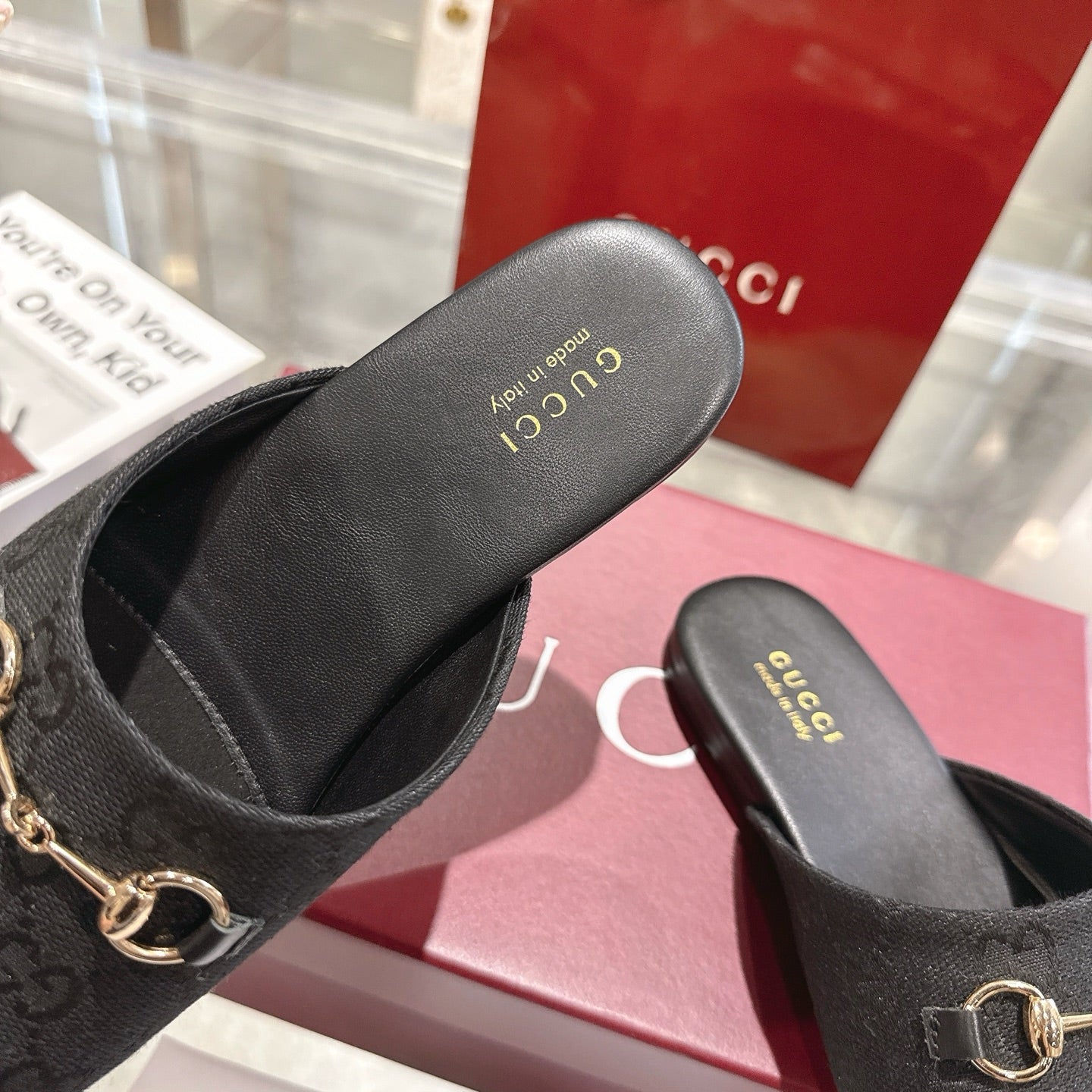 Gucci unisex mules showing insole and heel, dark monogram with gold horsebit hardware
