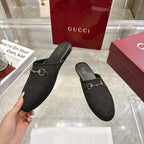 Gucci unisex slip-on mules with dark monogram upper and gold horsebit detail, hand-held