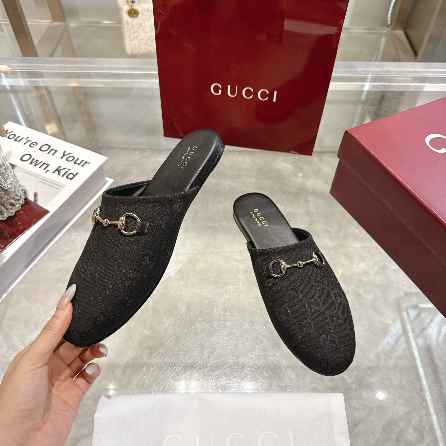 Gucci unisex slip-on mules with dark monogram upper and gold horsebit detail, hand-held
