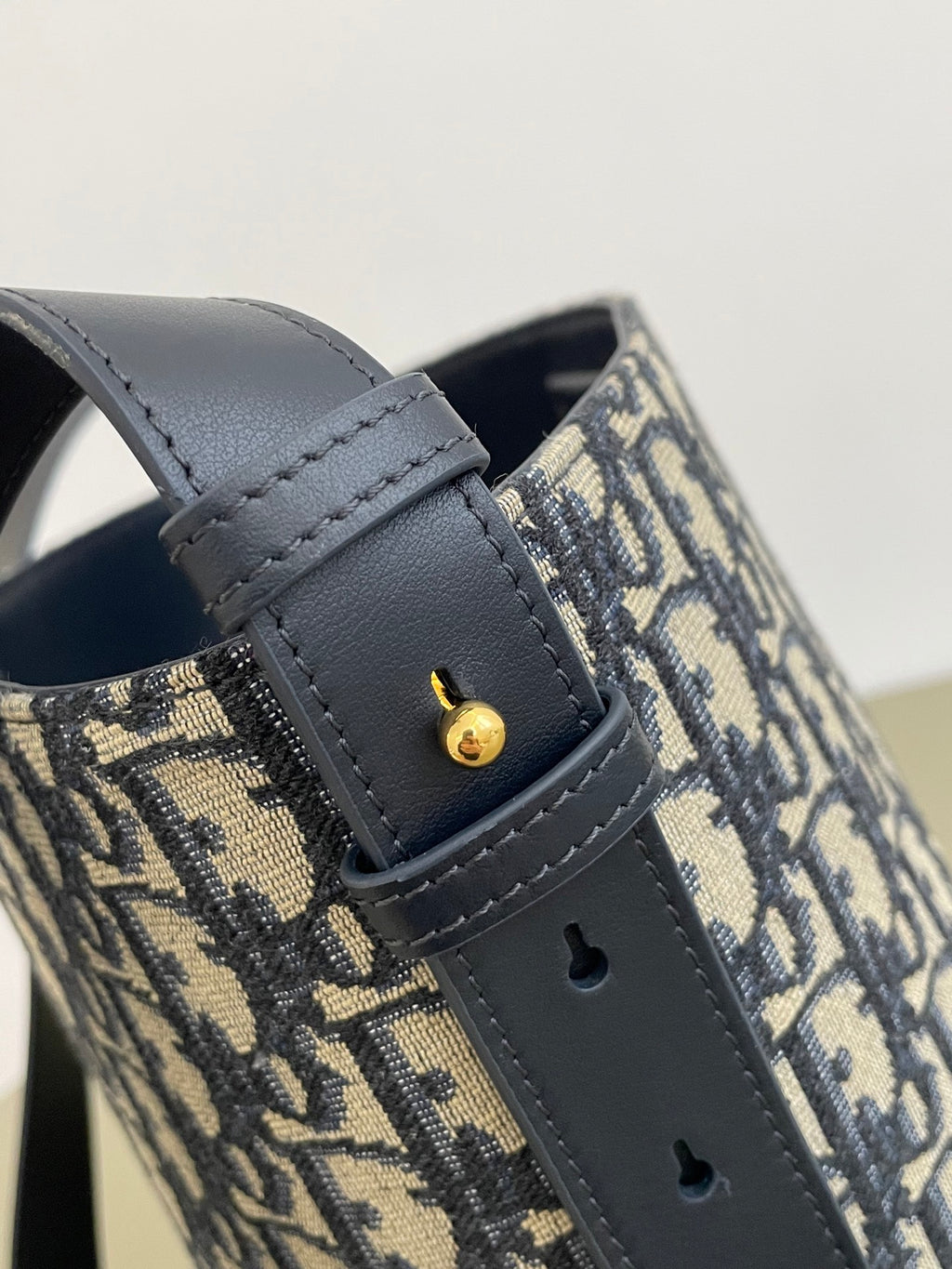 Navy leather strap with logo stud detail on Dior monogram bag