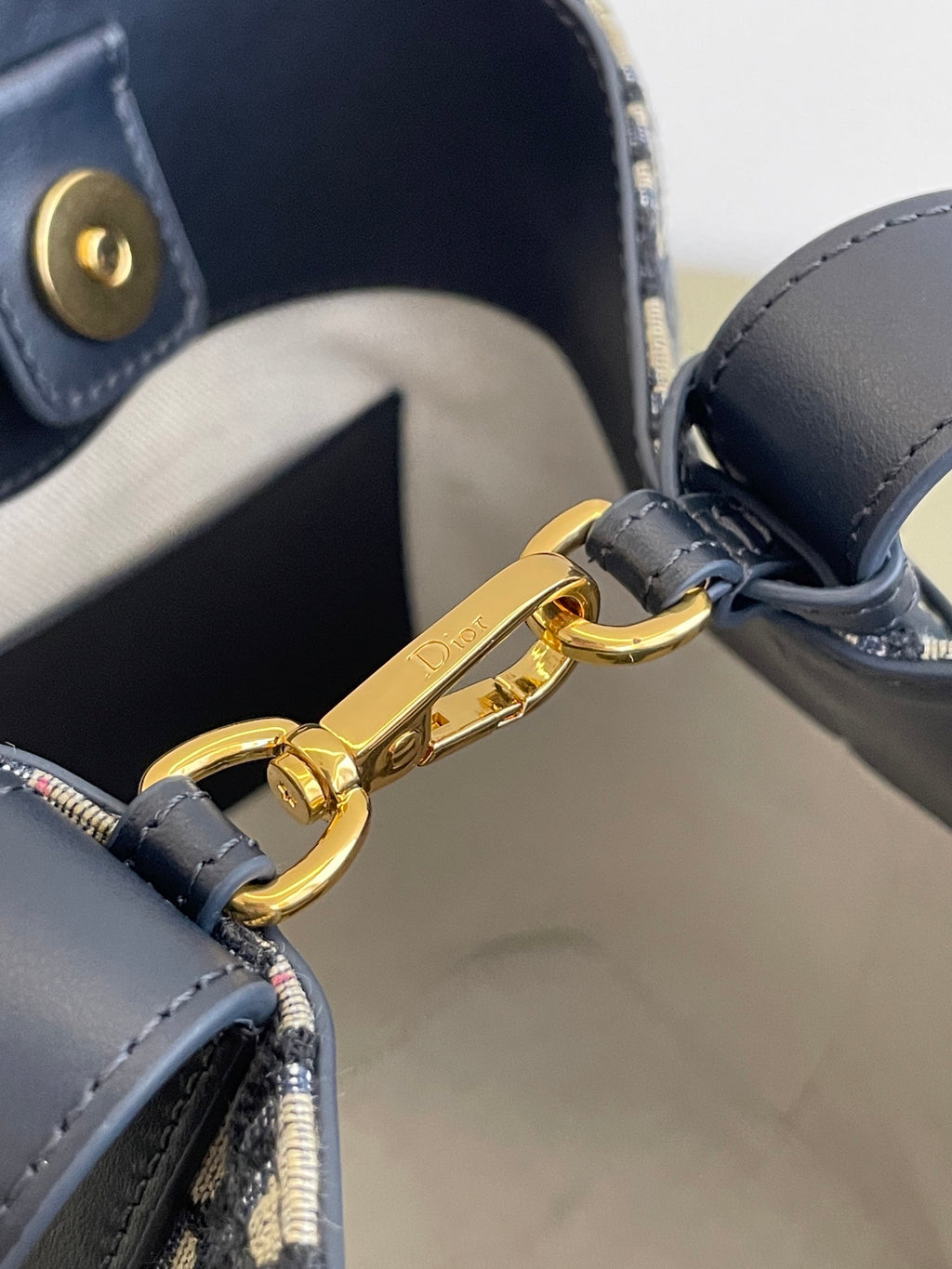 Gold clasp hardware on navy leather handle strap of Dior monogram bag