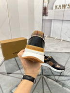 Black sneaker heel view in hand with tan-gold trim and cushioned sole