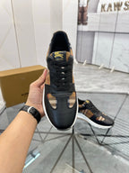 Black lace-up sneaker held up, textured sole and gold logo patch