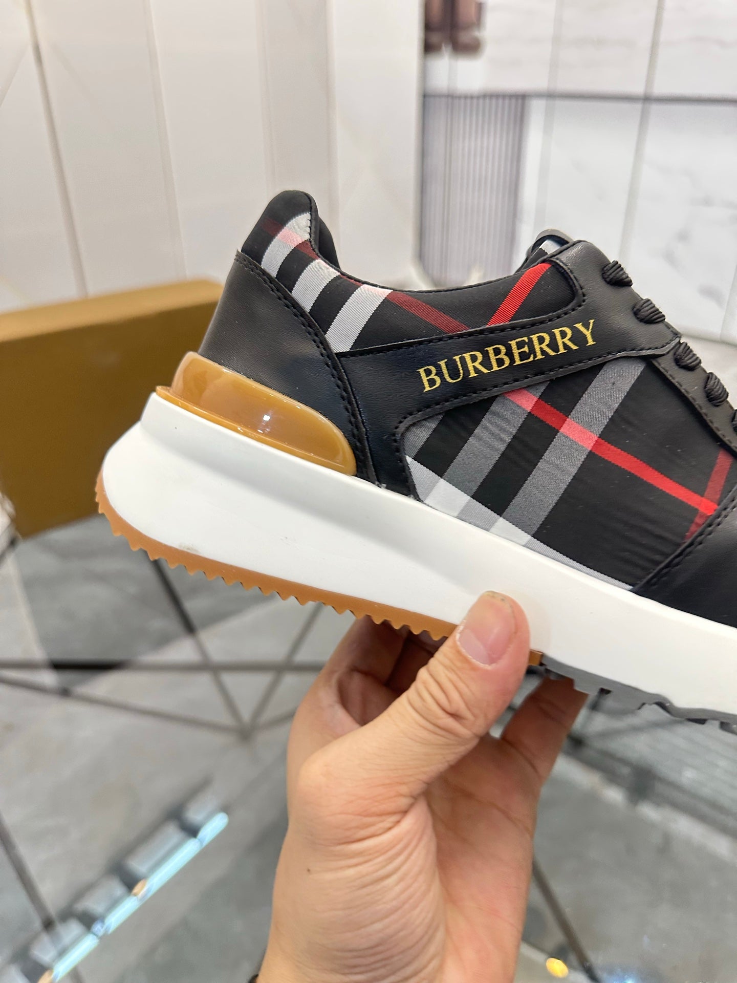 Black low-top sneaker with plaid side stripe and gum-colored outsole detail