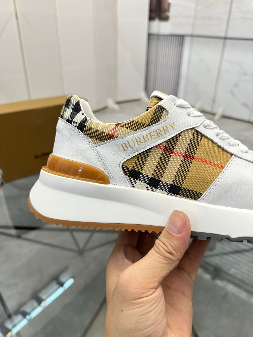 Burberry white sneaker showing plaid panel and stitched Burberry logo on the side