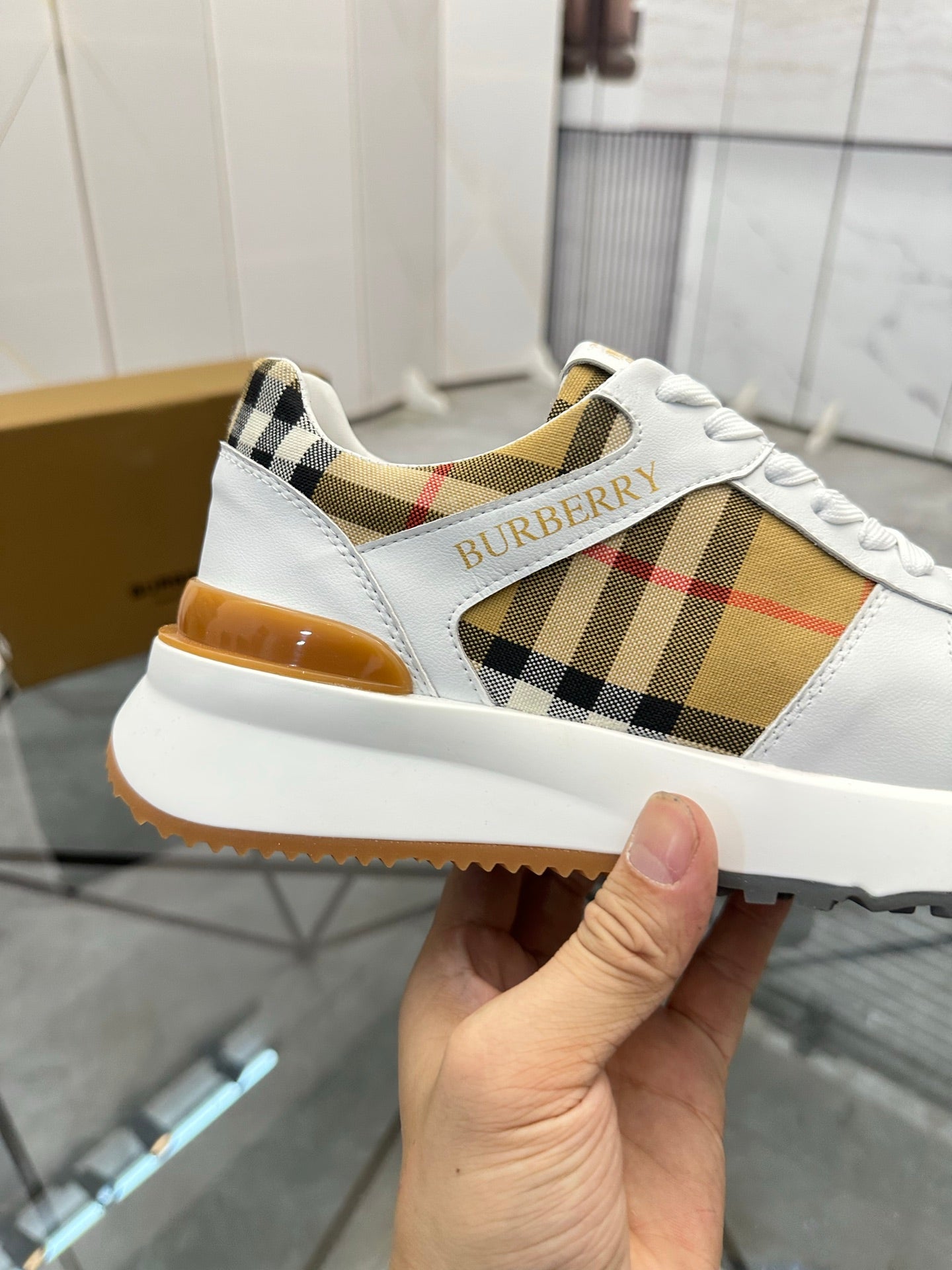 Burberry white sneaker showing plaid panel and stitched Burberry logo on the side