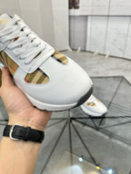 Burberry white sneaker close-up with lace, plaid insert, and gold-toned accent