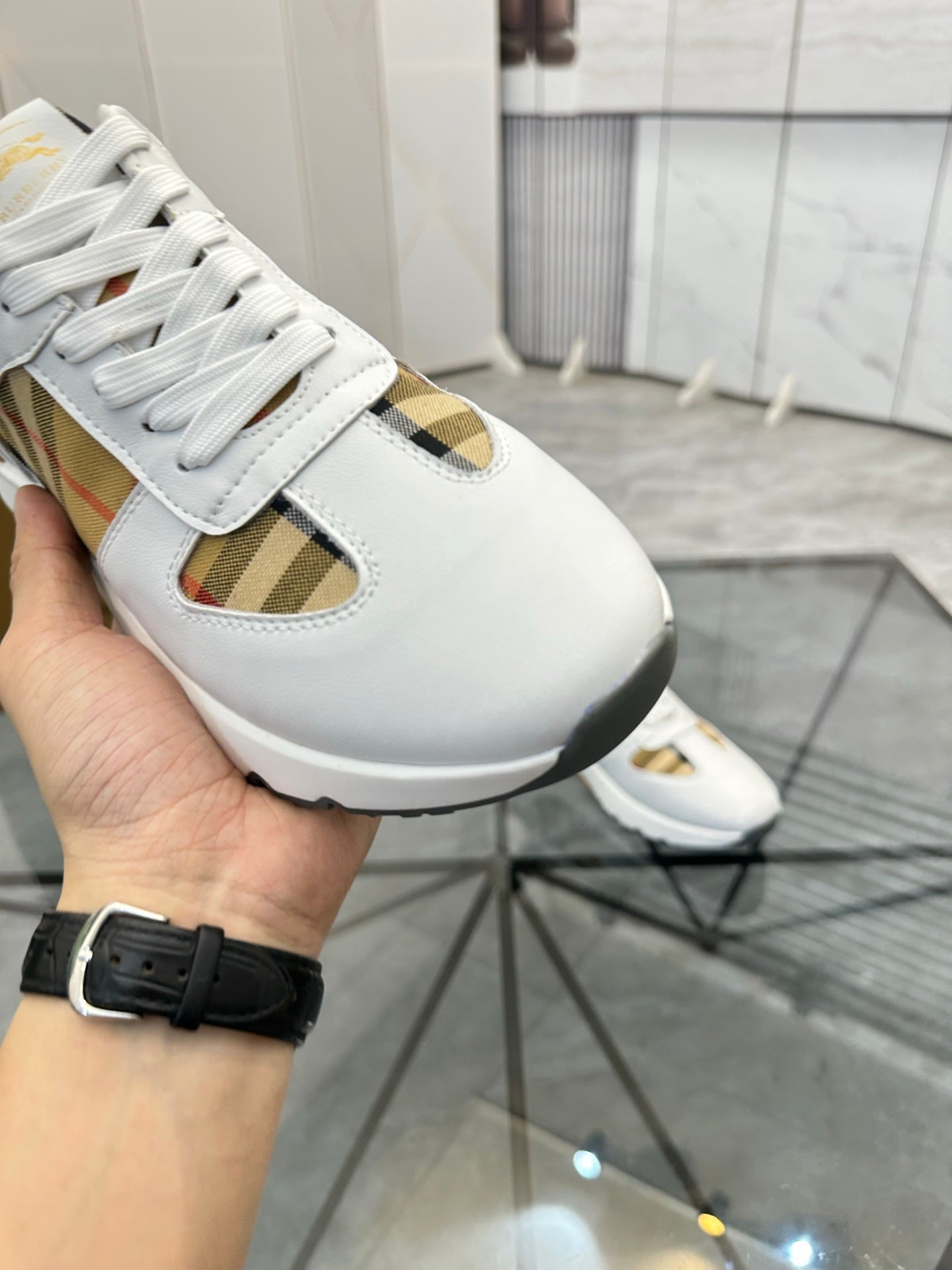 Burberry white sneaker close-up with lace, plaid insert, and gold-toned accent