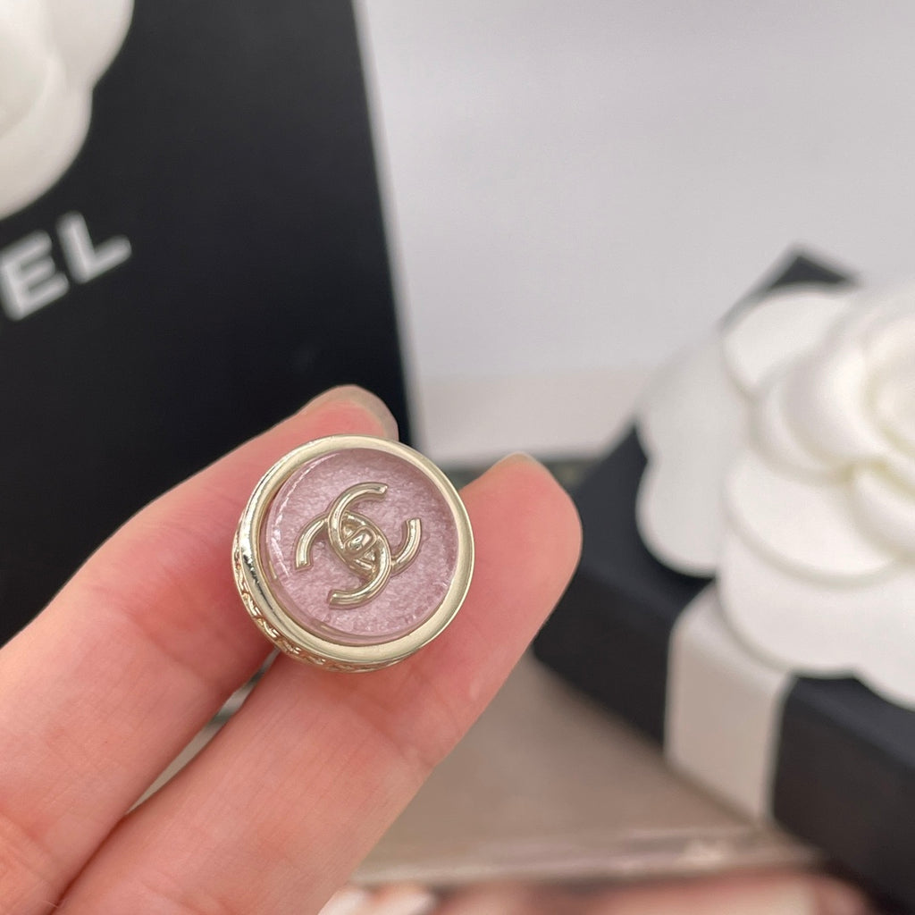 Close-up of a Chanel round stud earring with pink CC logo and gold border