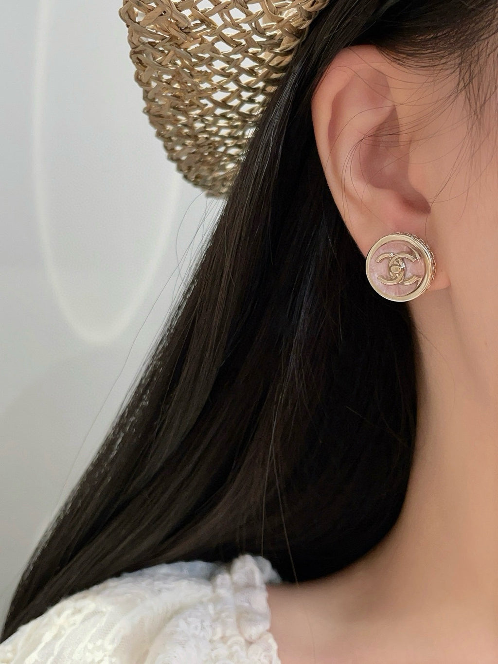 Chanel stud earring on ear with small round pink CC logo medallion