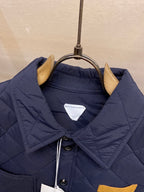 Navy quilted jacket with buttoned stand collar and inner label