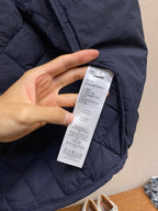 Navy quilted jacket sleeve with white size label