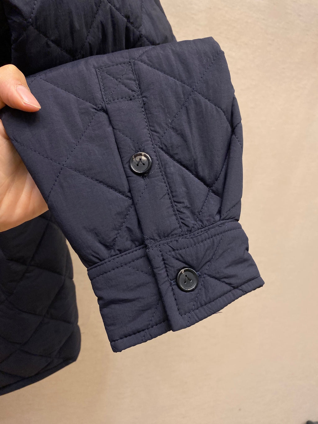 Navy quilted jacket cuff with two button tabs