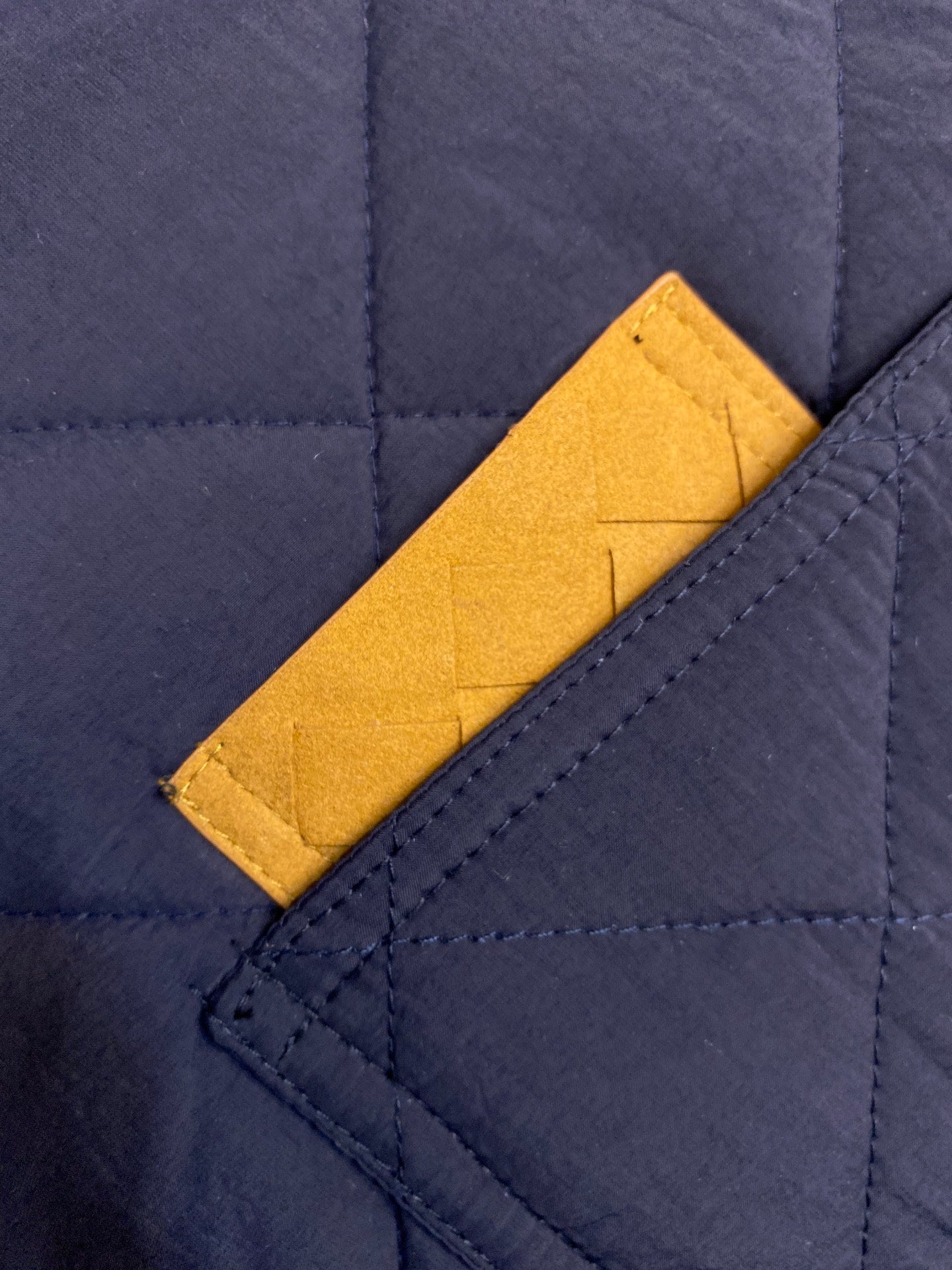 Navy quilted fabric with mustard yellow chest pocket and stitching