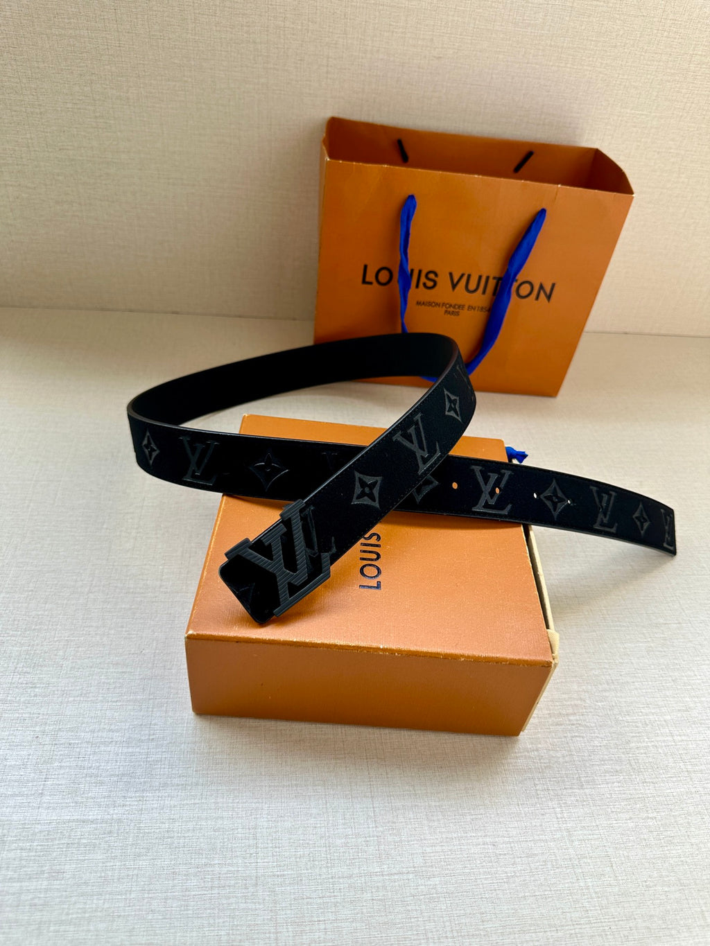 Dark navy leather belt with LV buckle and repeating monogram motifs, folded strap
