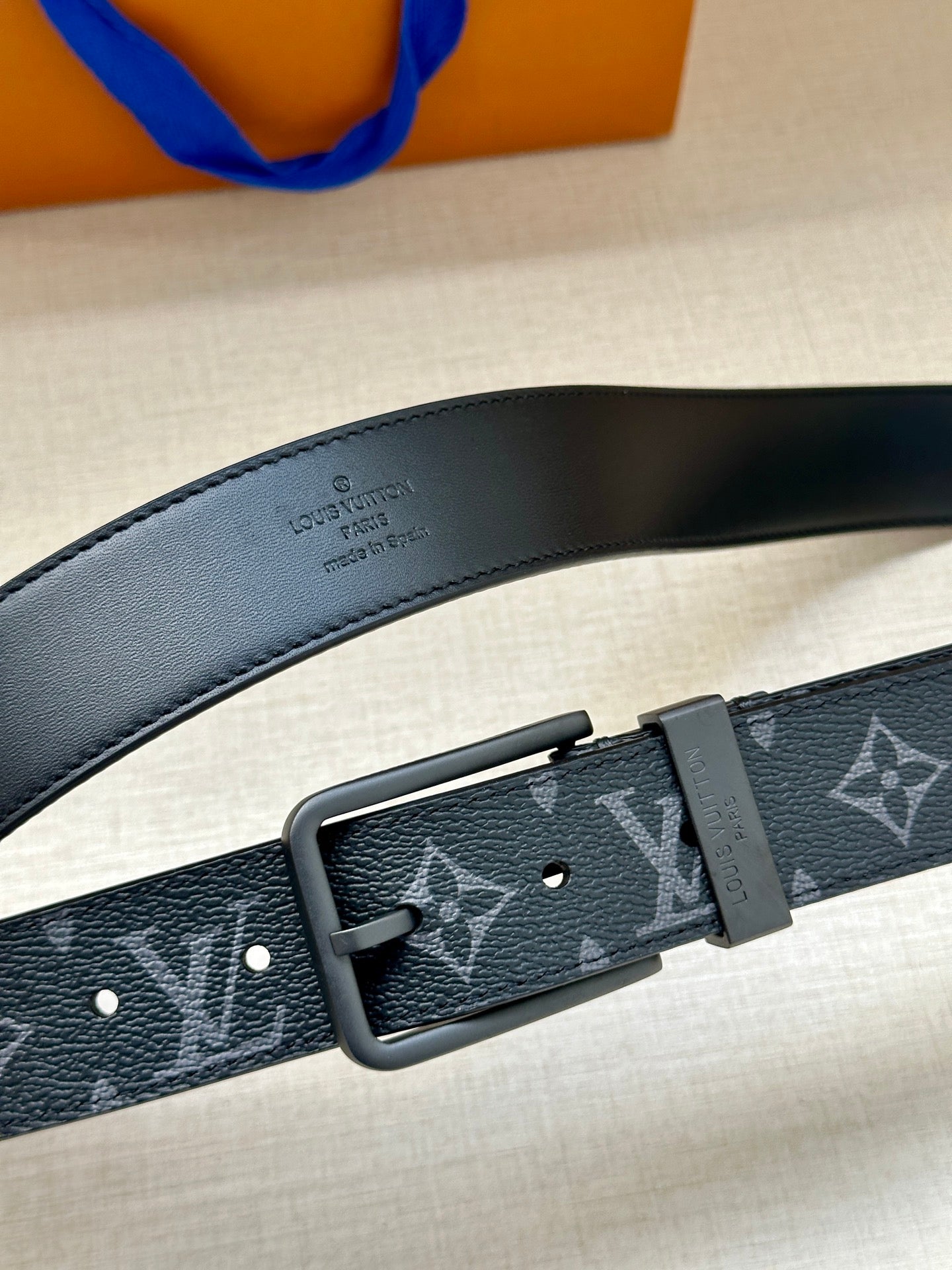 Louis Vuitton belt close-up: dark blue monogram strap with rectangular metal buckle