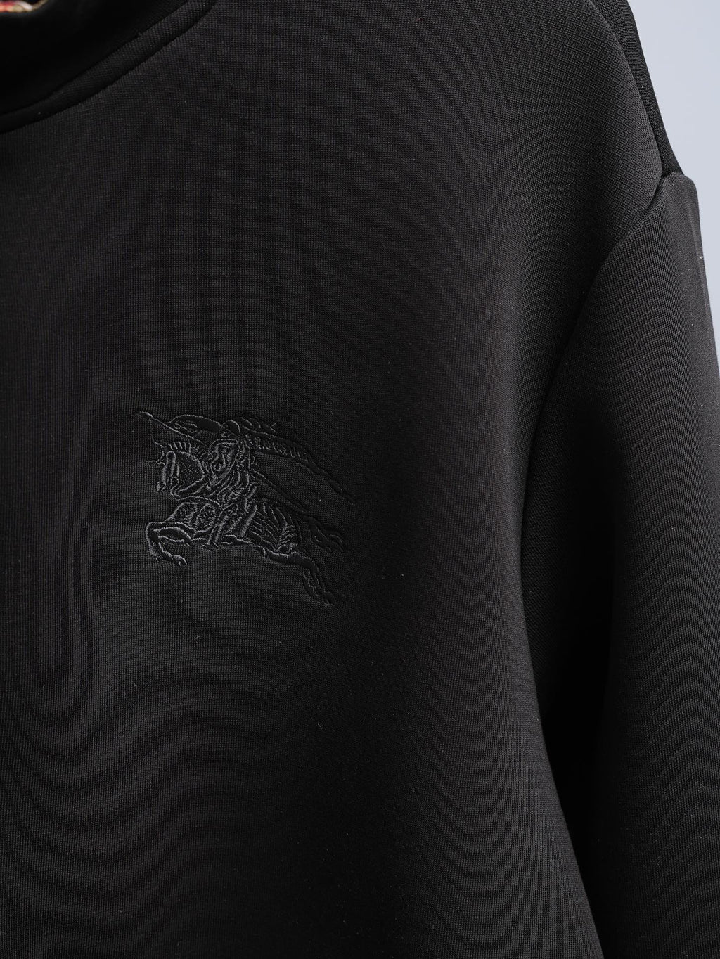 Black zip-up hoodie with embossed crest logo on chest