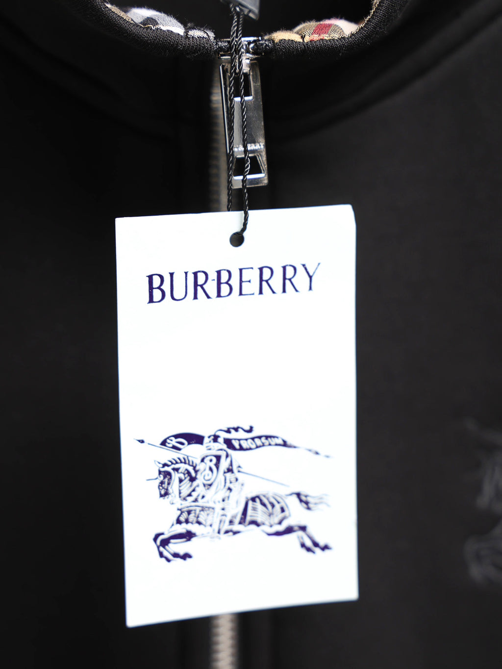 Black zip-up hoodie with hanging Burberry logo tag and silver zipper pull