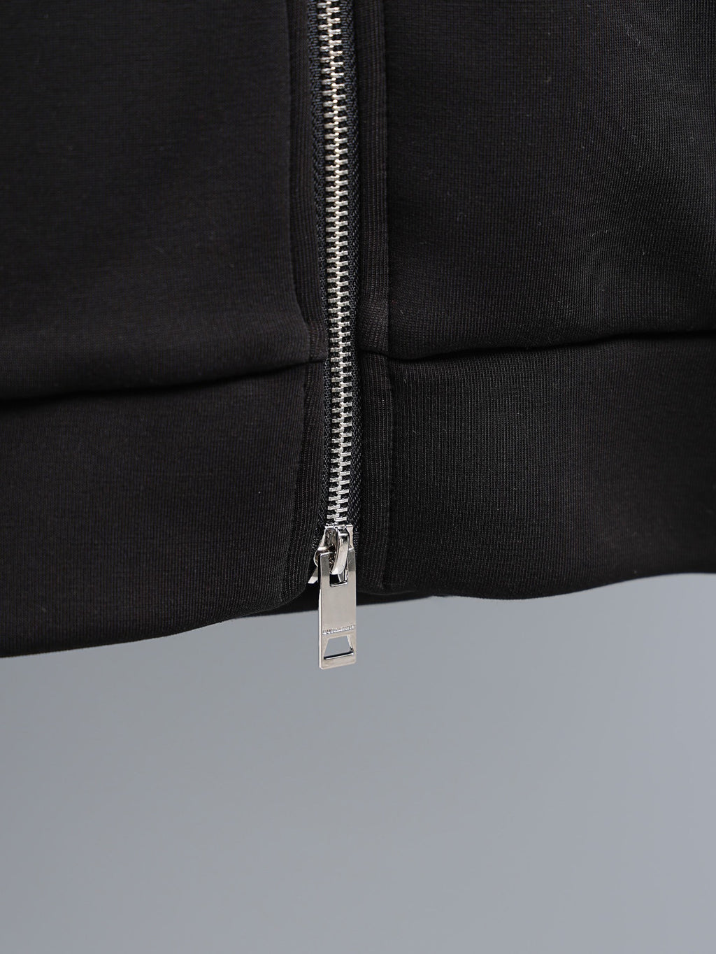 Black zip-up hoodie close-up of silver zipper and pull