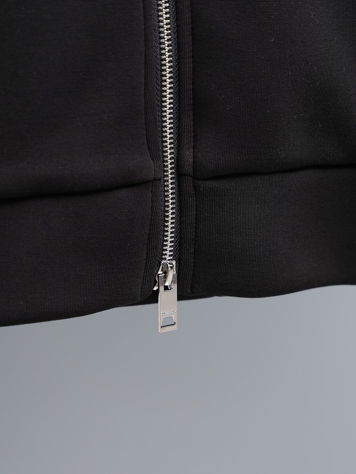 Black zip-up hoodie close-up of silver zipper and pull