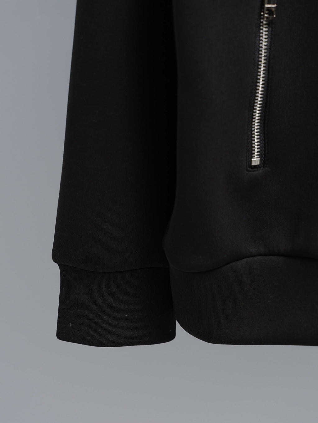 Black zip-up hoodie with curved hem and small silver side zipper