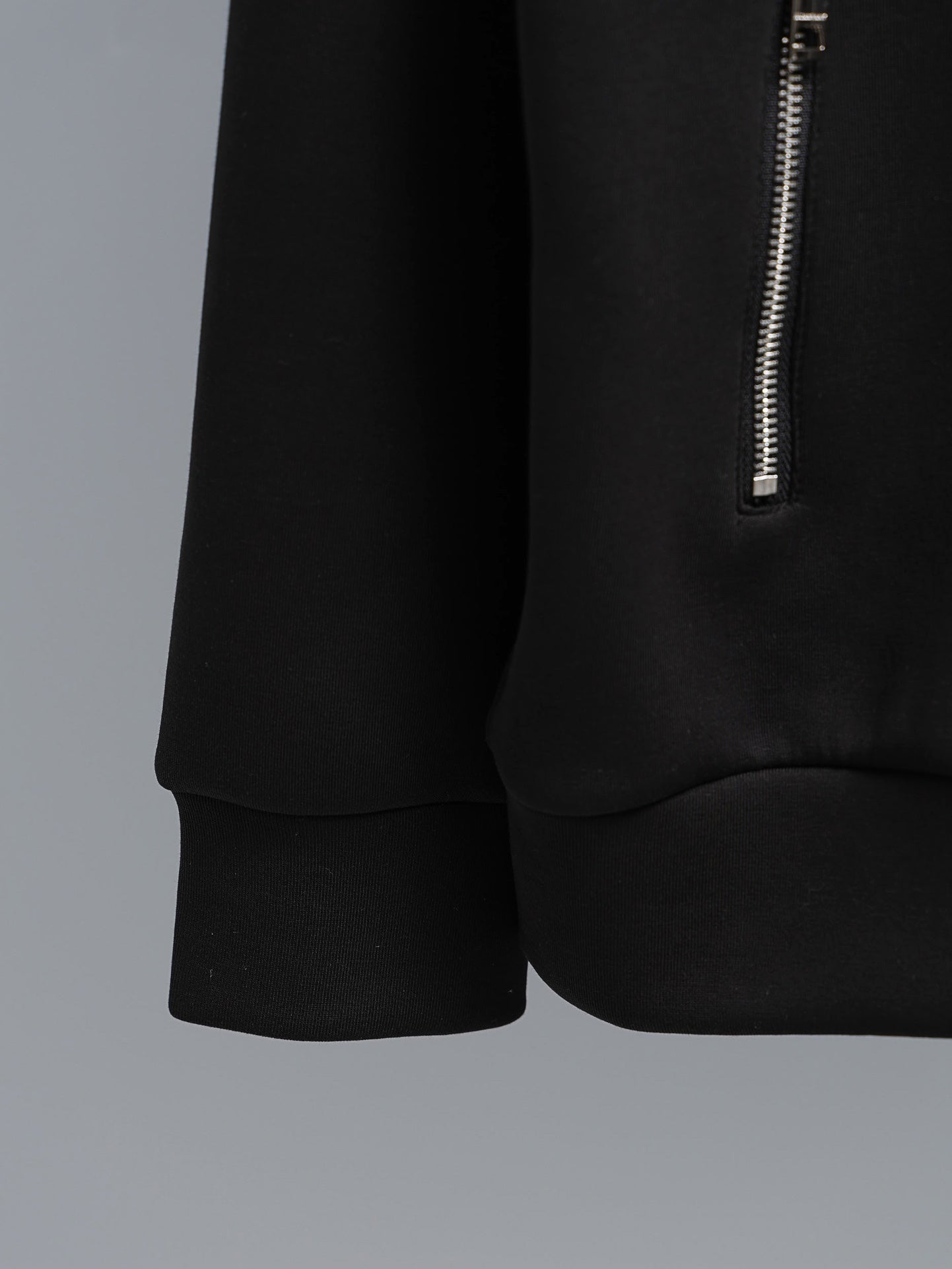 Black zip-up hoodie with curved hem and small silver side zipper
