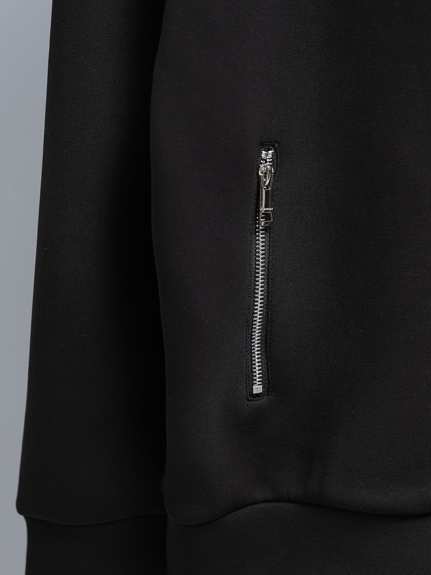 Black zip-up hoodie sleeve with small silver zipper detail