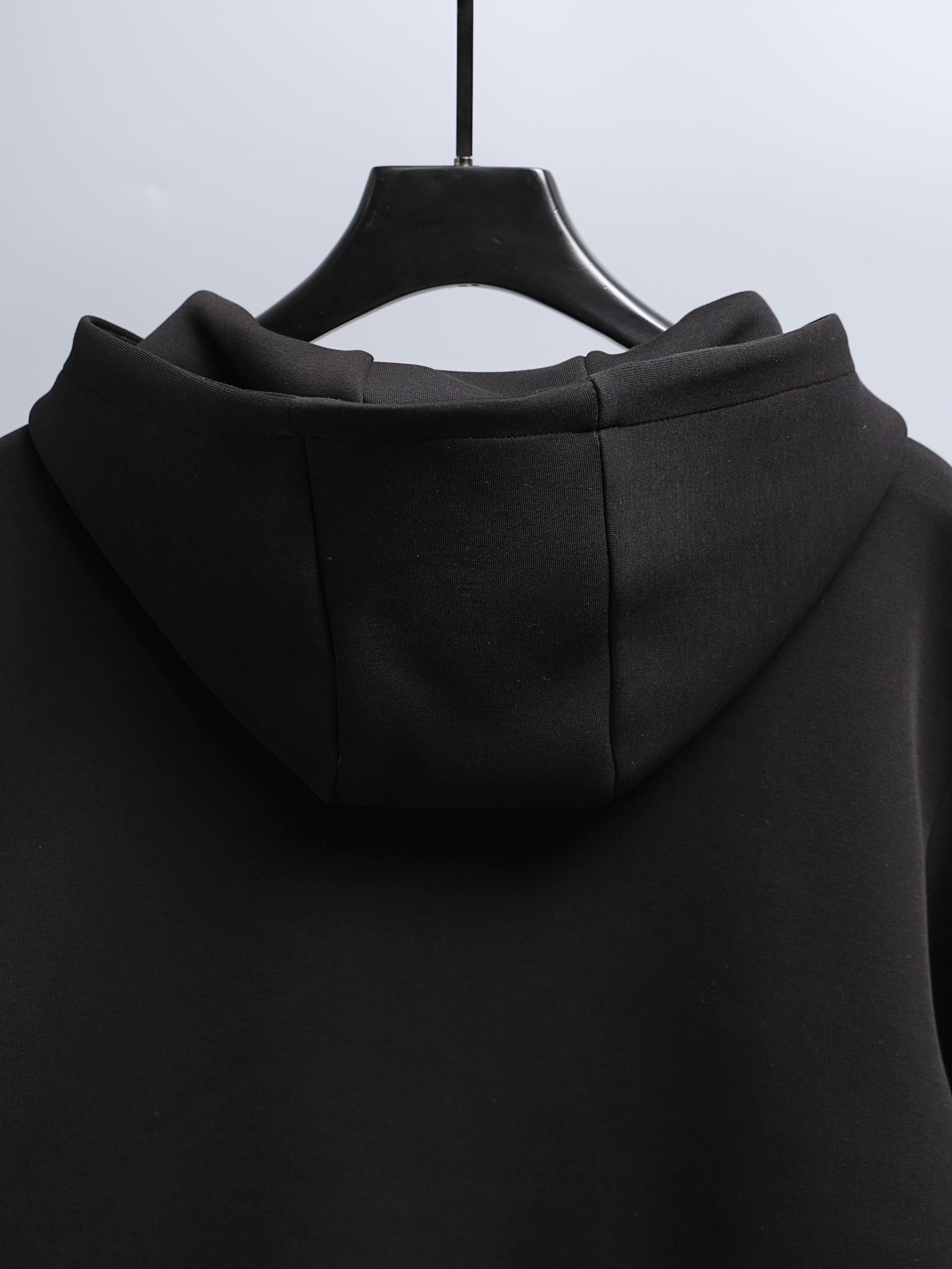 Black zip-up hooded jacket with hood and back seam