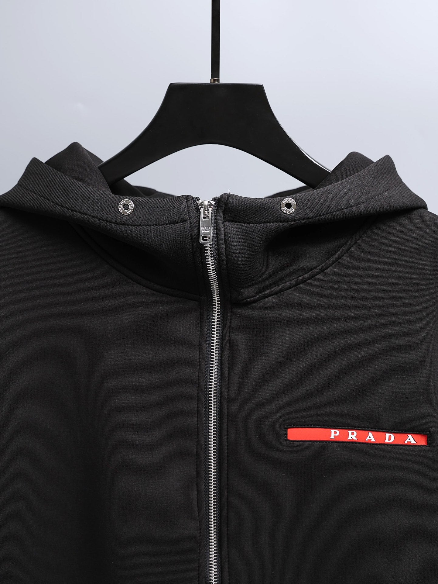 Black zip-up hooded jacket with metal zipper and Prada logo label
