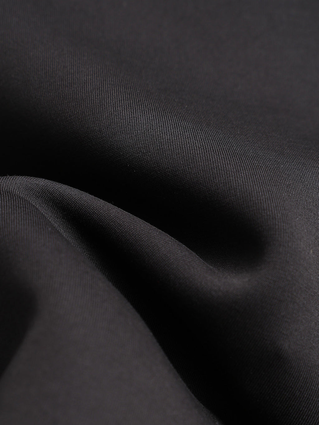 Black jacket fabric close-up with smooth, woven texture