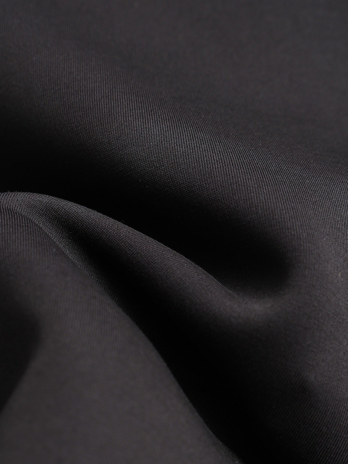 Black jacket fabric close-up with smooth, woven texture