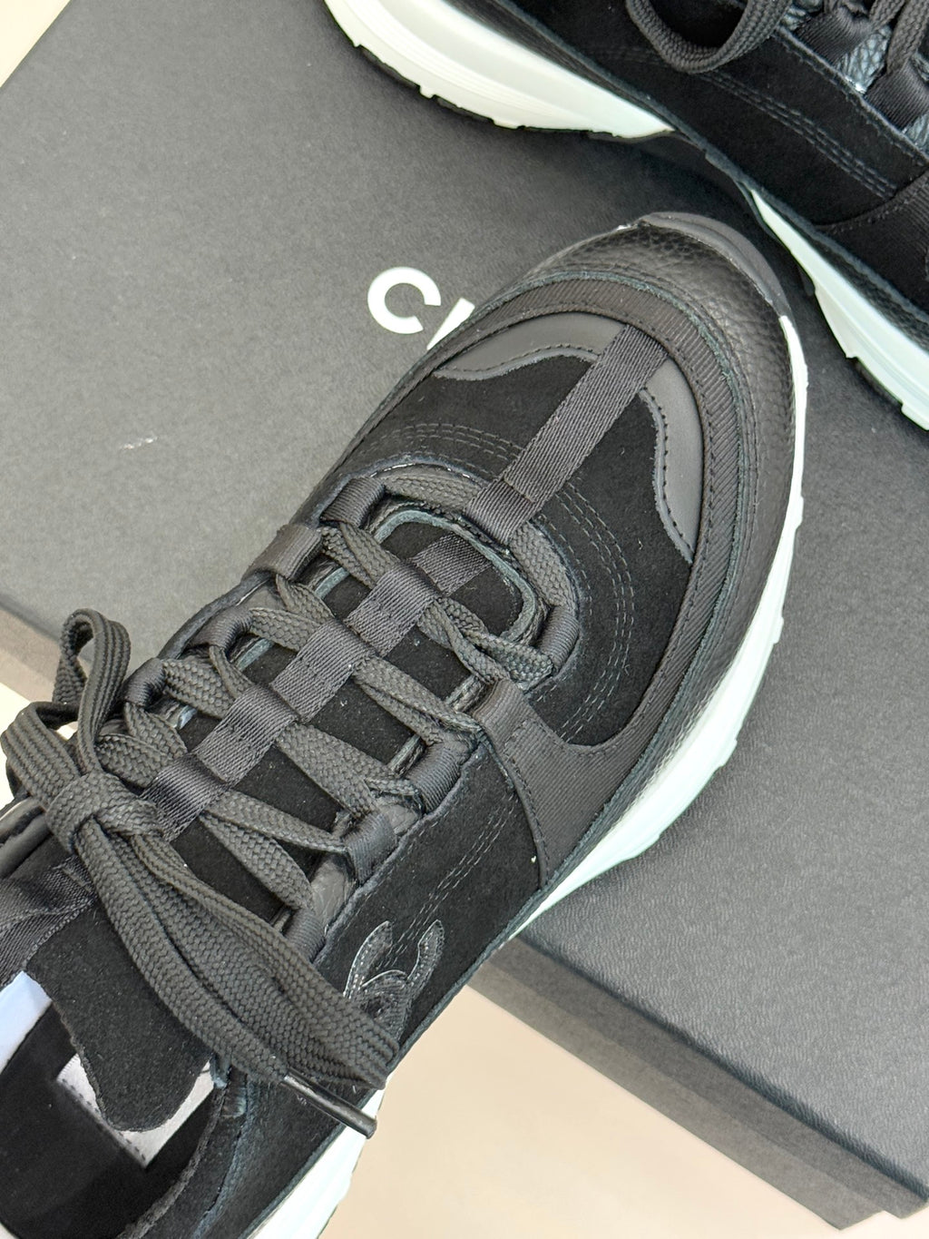 Chanel women’s sneakers close-up: dark charcoal lace-up upper with white-trimmed sole.
