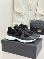 Chanel women’s lace-up sneakers, dark black with white rubber sole and small logo detail.