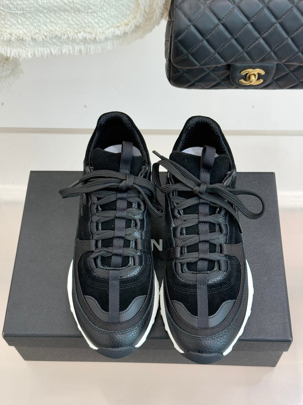 Chanel women’s lace-up sneakers, dark black, front view with white rubber soles.