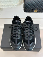 Chanel women’s lace-up sneakers, dark black, front view with white rubber soles.