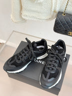Chanel women’s lace-up sneakers, dark black, shown from above on a gray display box.