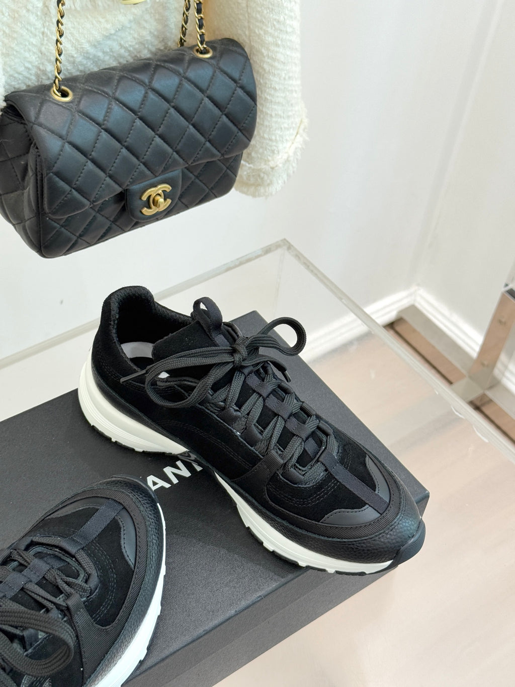 Chanel women’s lace-up sneakers in dark black, angled side view on a gray box.