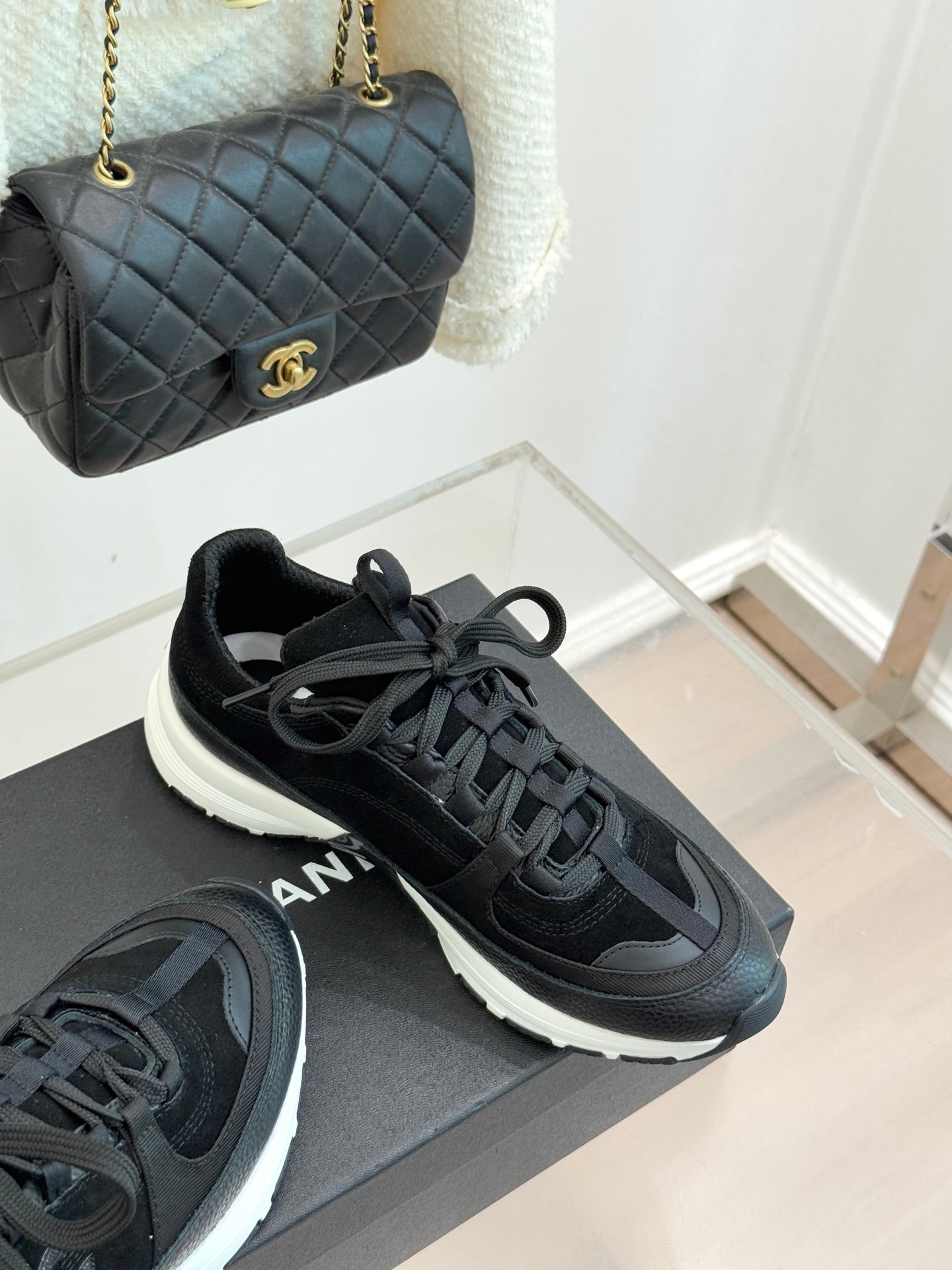 Chanel women’s lace-up sneakers in dark black, angled side view on a gray box.