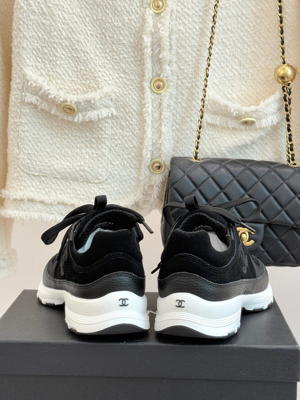 Chanel women’s lace-up sneakers, dark black, rear view with white rubber heel soles.