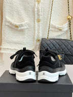 Chanel women’s lace-up sneakers, dark black, rear view with white rubber heel soles.