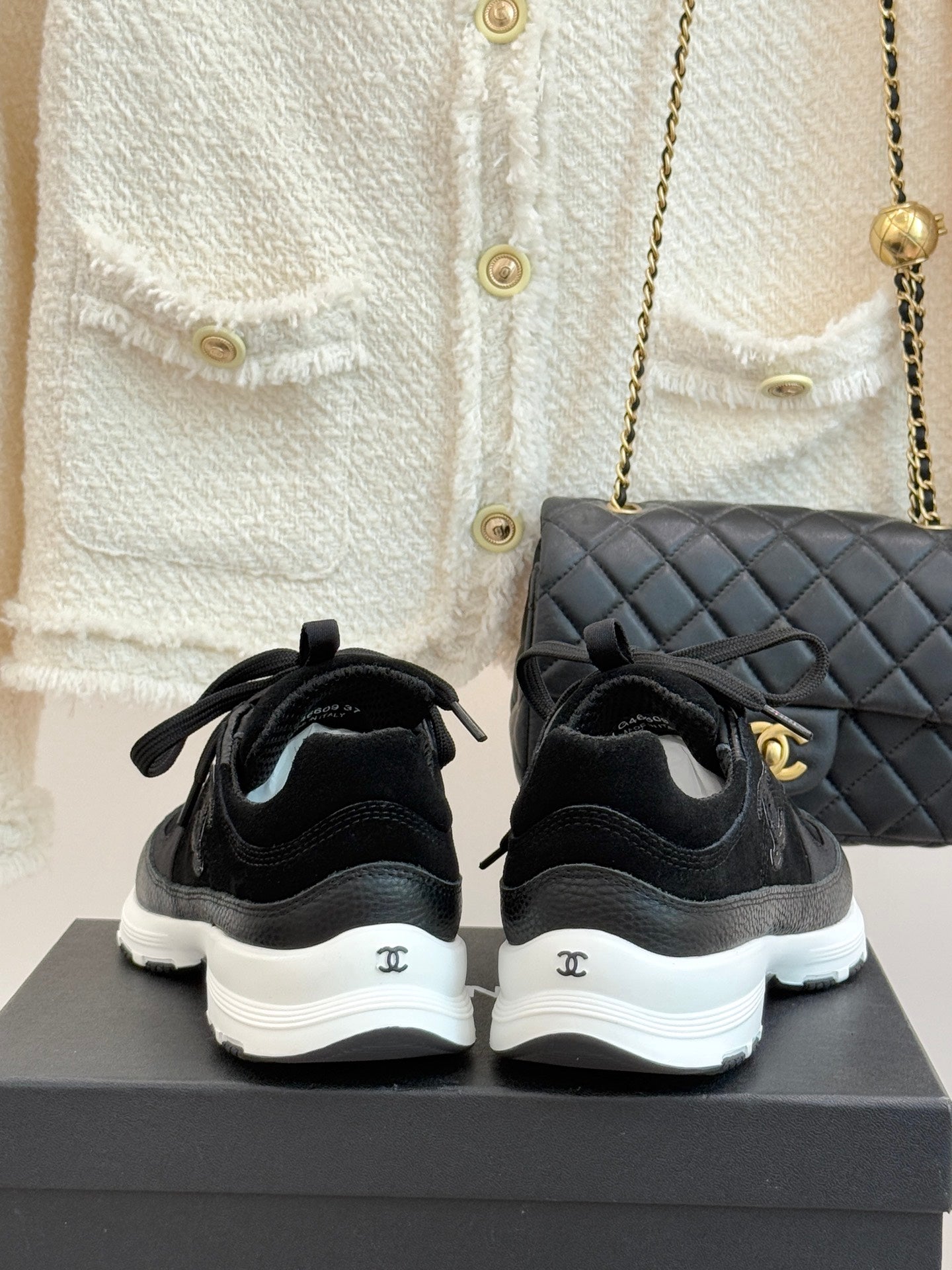 Chanel women’s lace-up sneakers, dark black, rear view with white rubber heel soles.