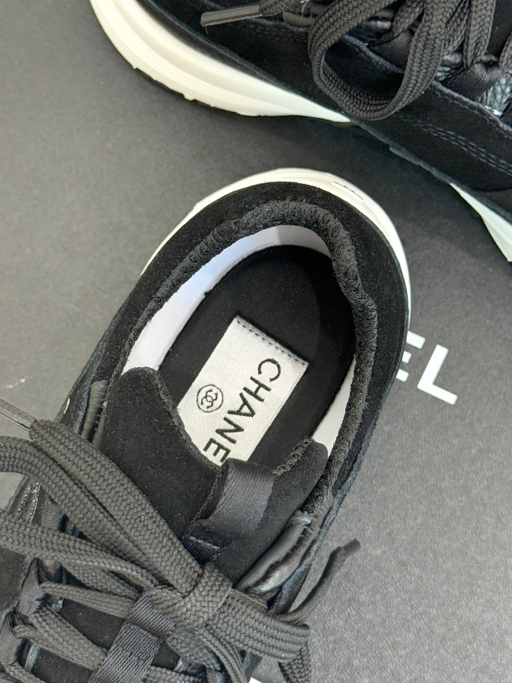 Chanel sneaker close-up: dark charcoal heel collar and white-lined insole label.