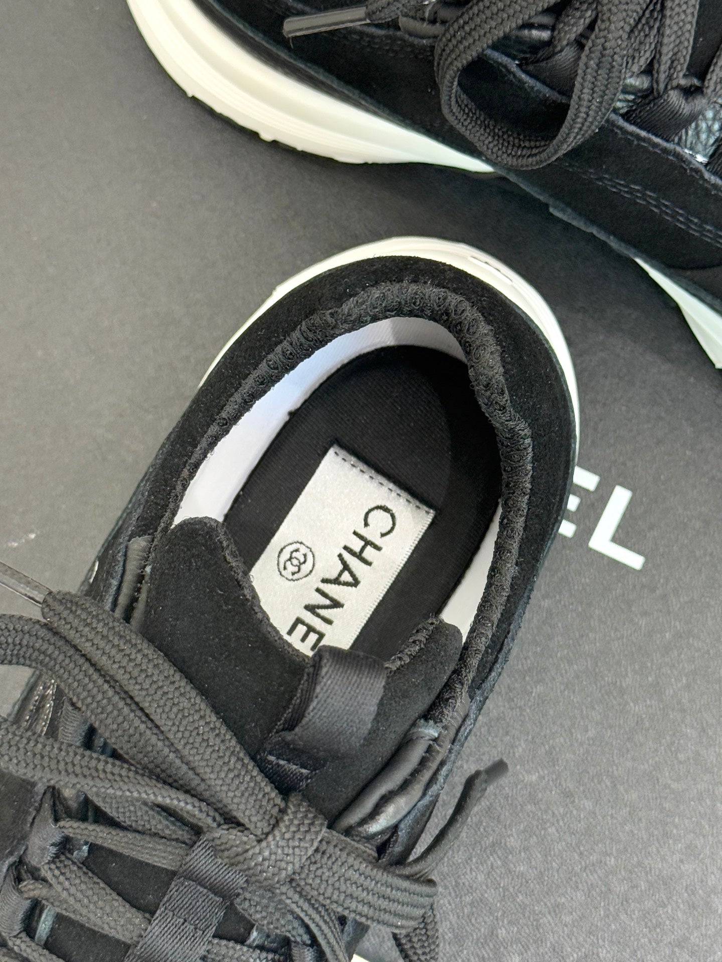 Chanel sneaker close-up: dark charcoal heel collar and white-lined insole label.