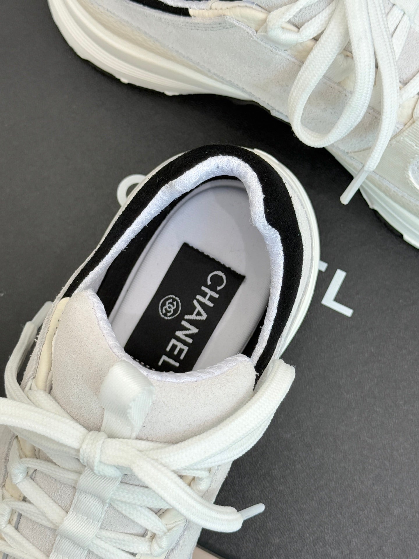 Chanel sneaker inside view showing “CHANEL” on tongue label and white laces